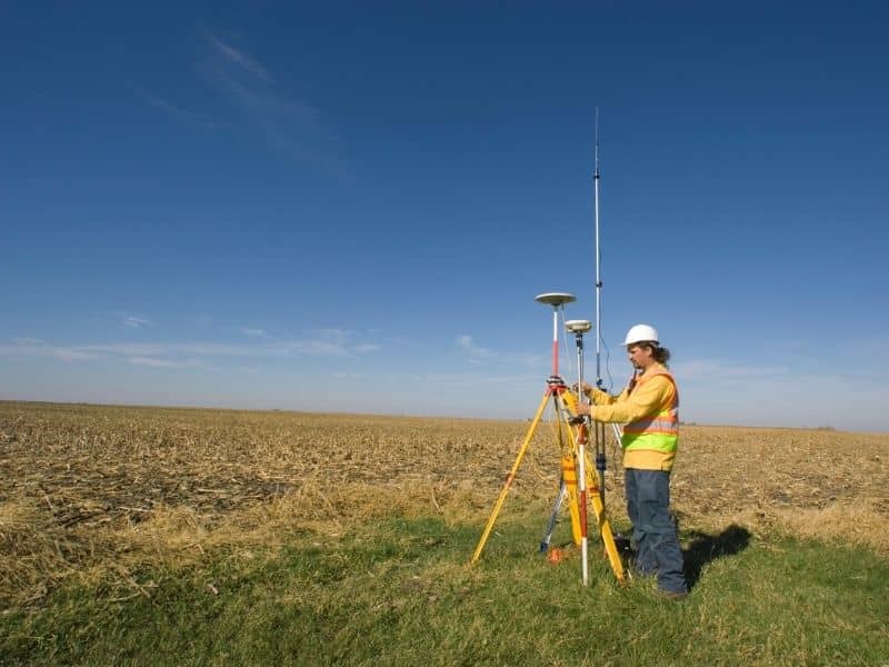 Land surveyor using GPS equipment to evaluate a large estate property for future residential home sites.